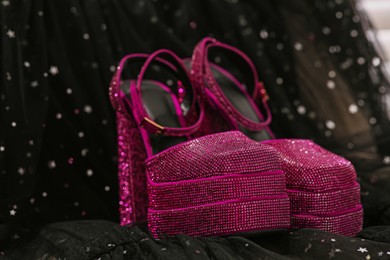 Photo of New pink high heeled shoes with platform and square toes on black cloth, closeup