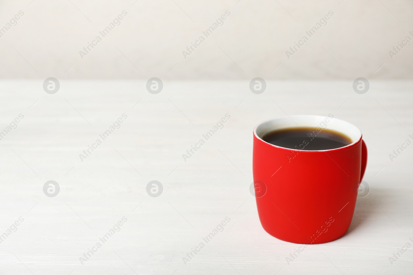 Photo of Red ceramic cup with hot aromatic coffee on table