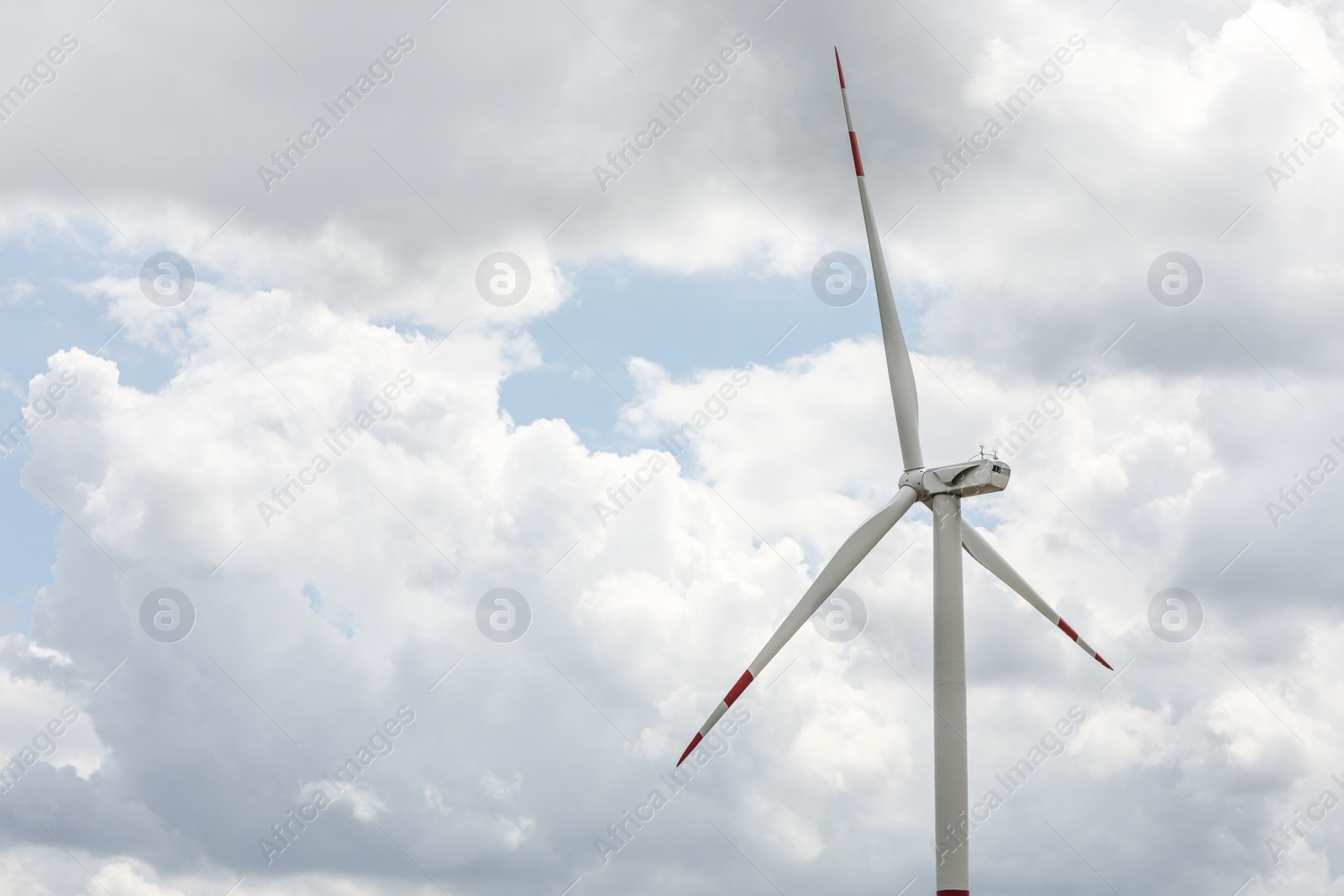 Photo of Modern wind turbine against cloudy sky, closeup. Alternative energy source