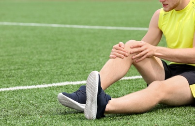 Photo of Man in sportswear suffering from knee pain at soccer field, closeup