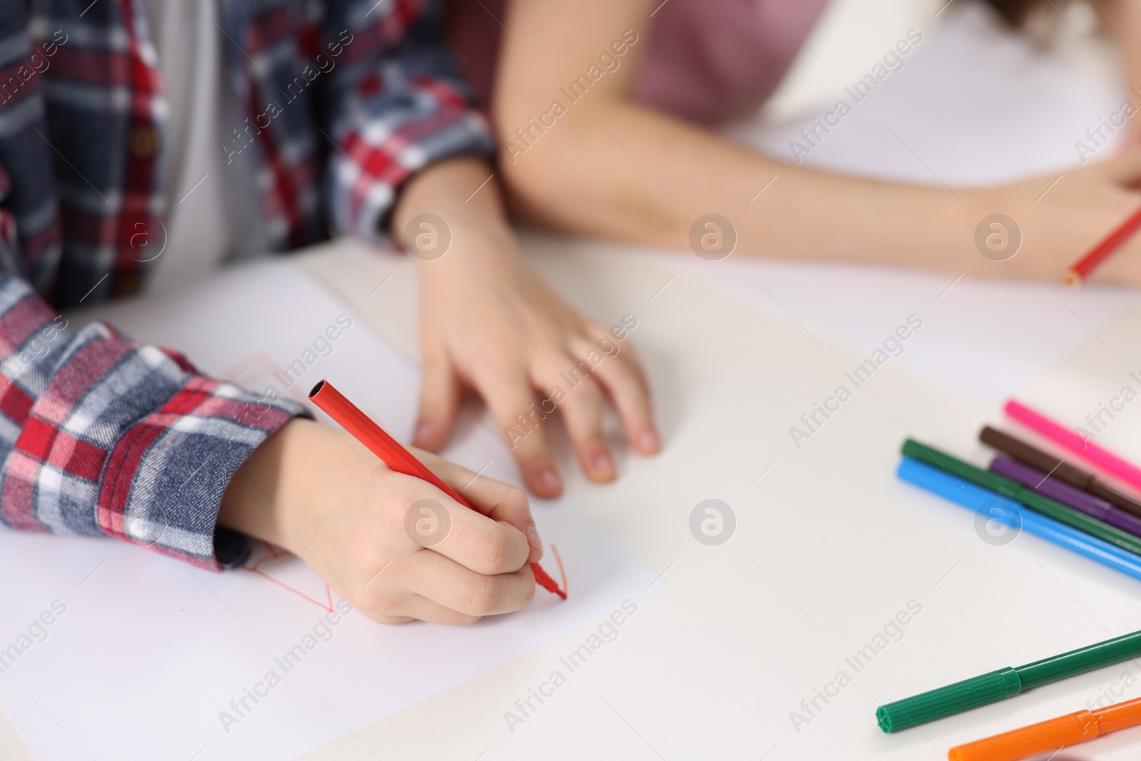 Photo of Brother and sister drawing at white table, closeup