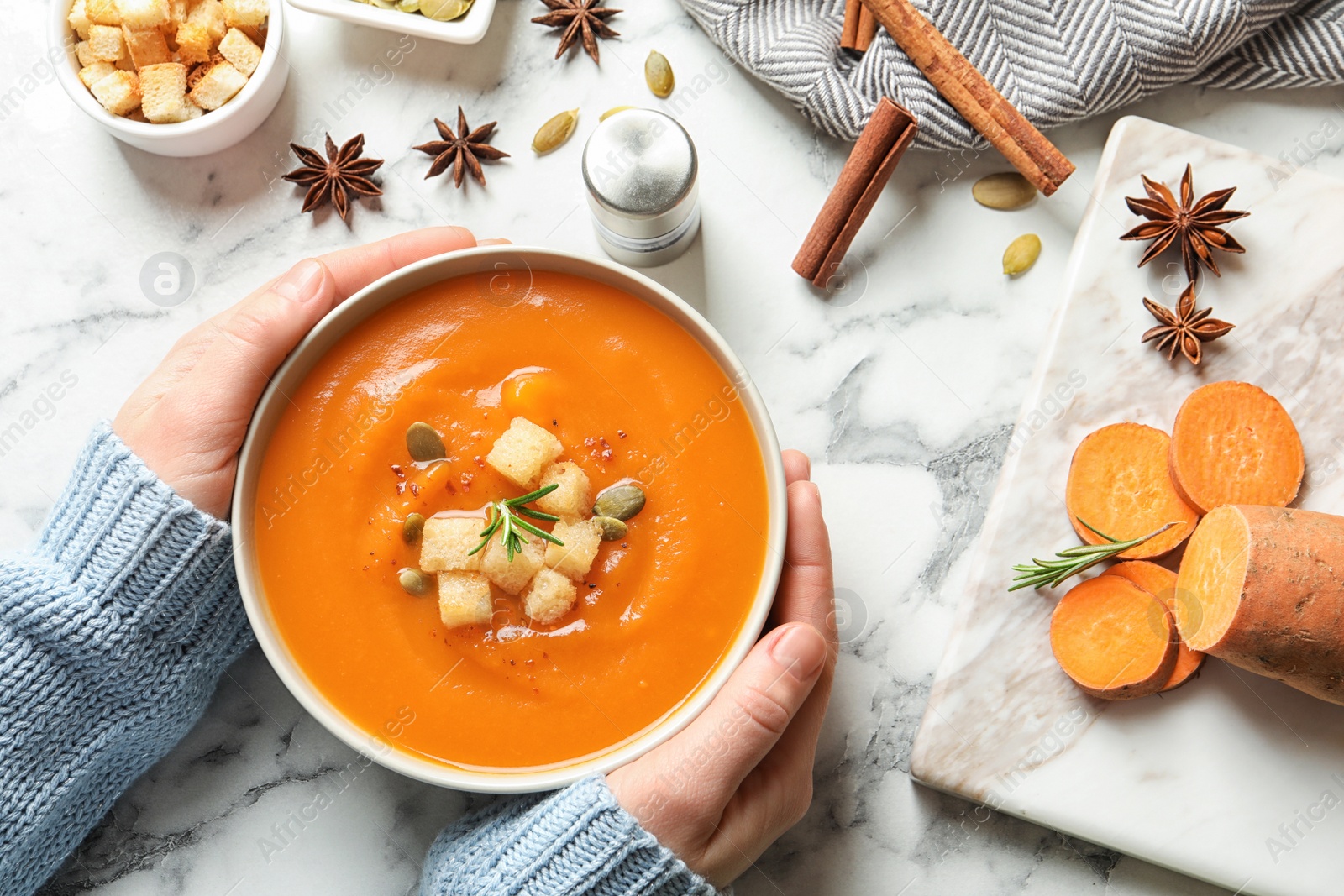 Photo of Woman with bowl of tasty sweet potato soup at table, top view