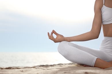 Young woman practicing zen meditation on beach, closeup. Space for text