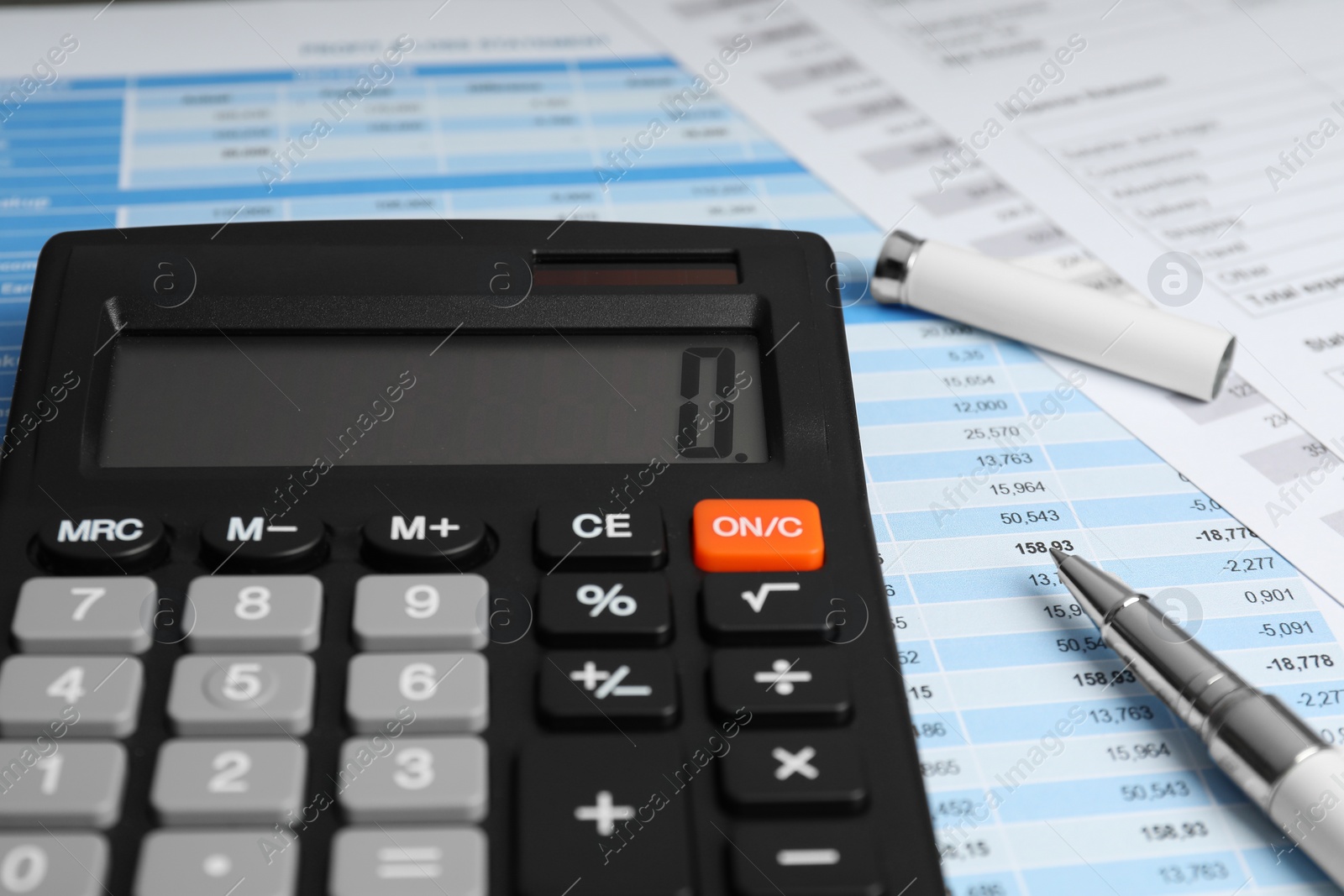 Photo of Calculator and pen on documents, closeup view