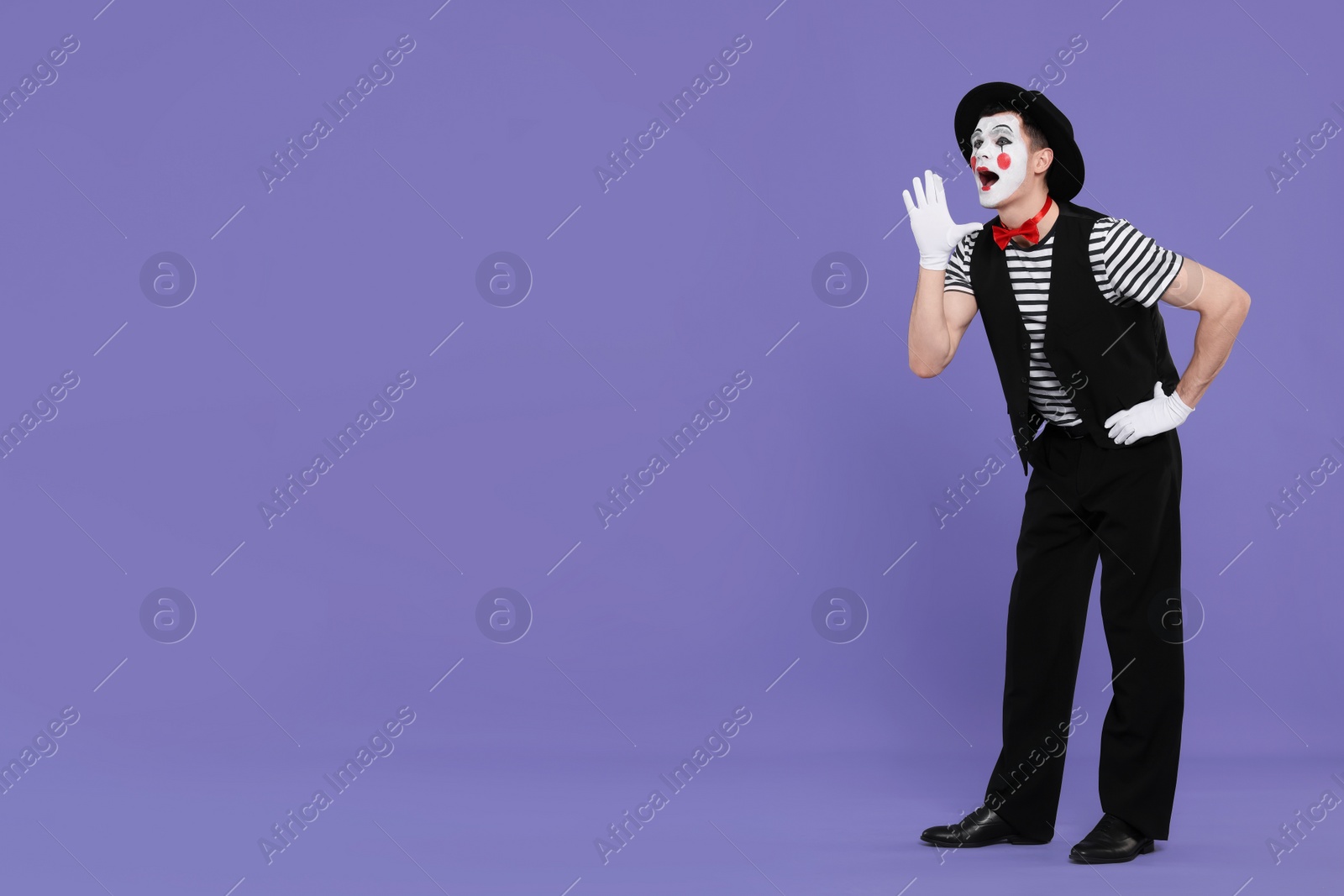 Photo of Funny mime artist in hat screaming on purple background. Space for text