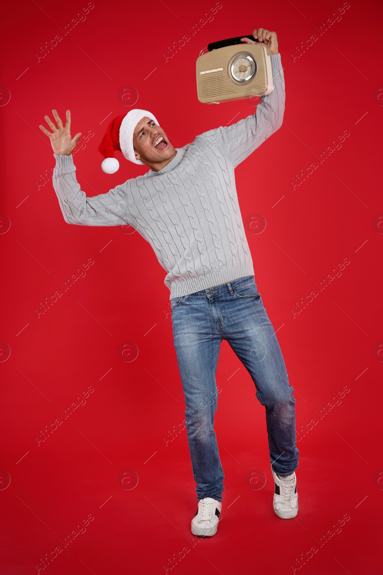 Photo of Emotional man with vintage radio on red background. Christmas music