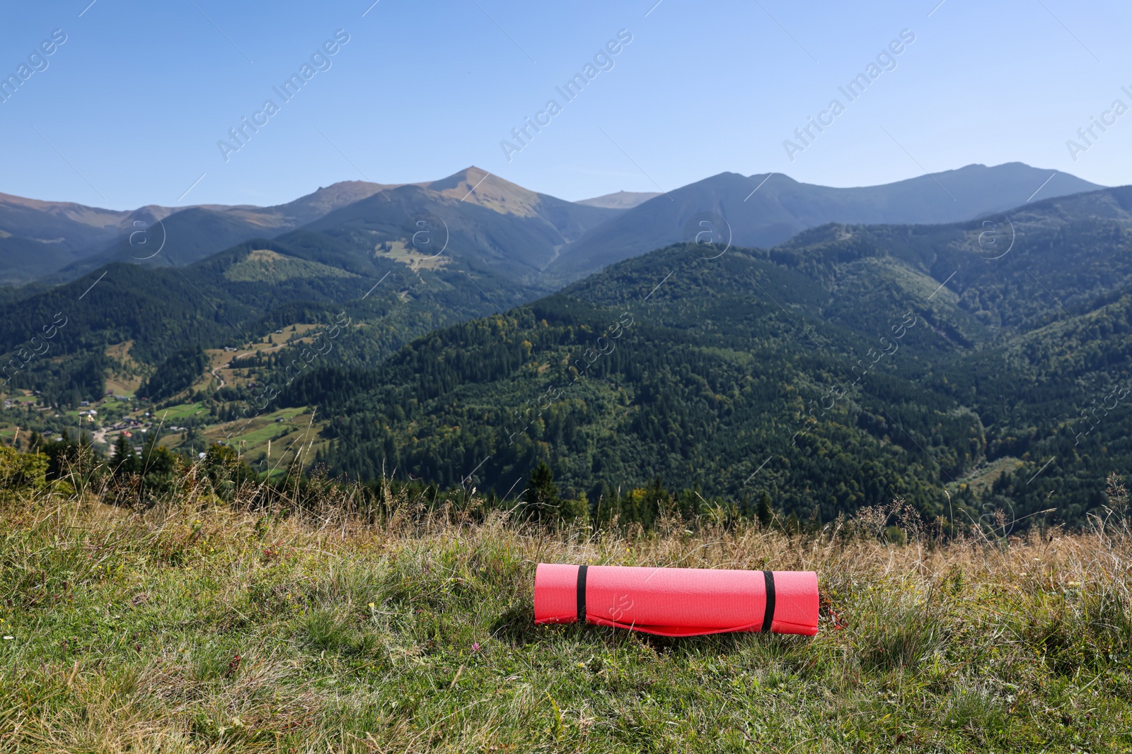 Photo of Rolled sleeping pad on grass in mountains, space for text