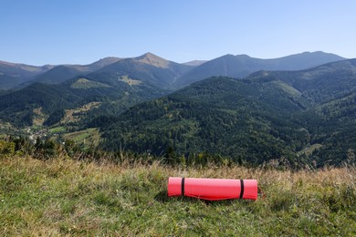 Photo of Rolled sleeping pad on grass in mountains, space for text