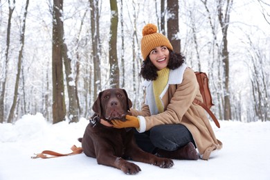 Photo of Woman with adorable Labrador Retriever dog in snowy park