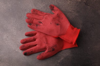 Photo of Pair of red gardening gloves on brown textured table, top view