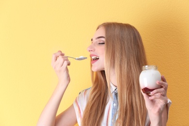 Young woman with yogurt on color background