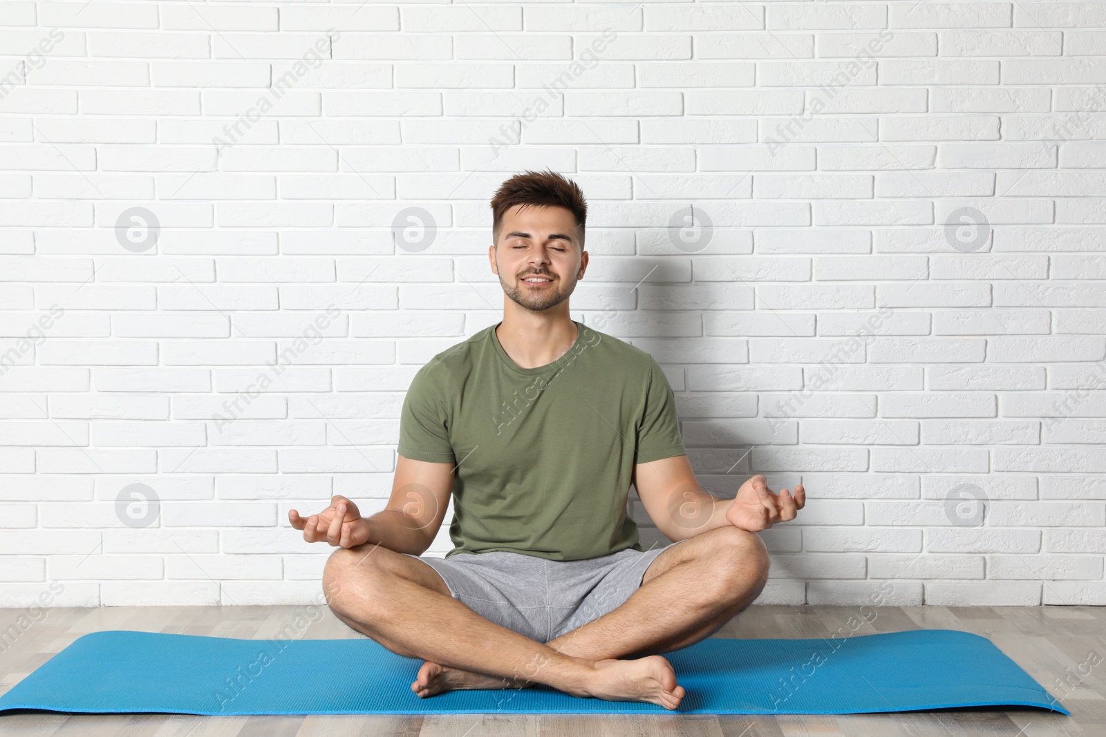 Photo of Young man practicing zen yoga near white brick wall