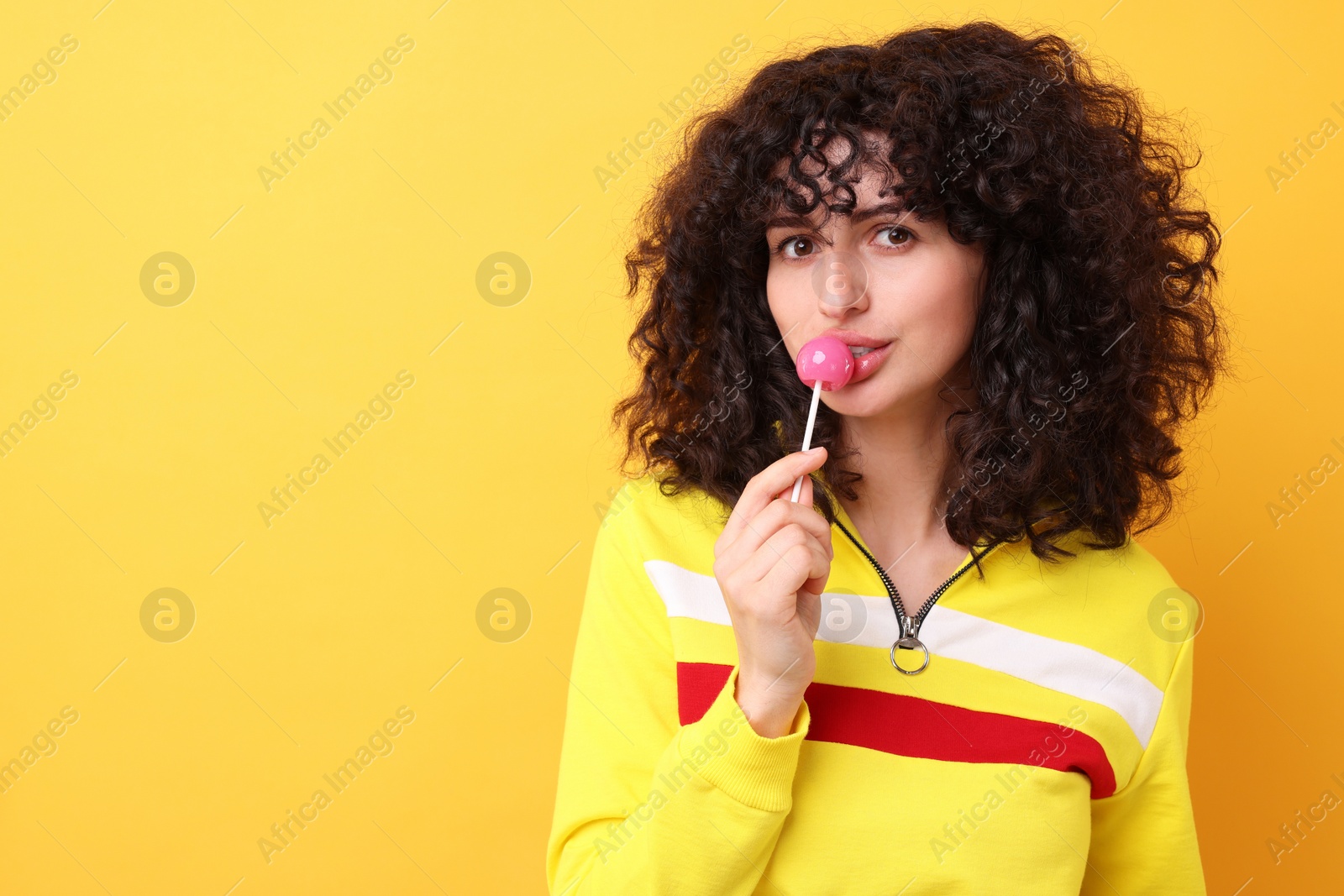 Photo of Beautiful woman with lollipop on yellow background, space for text