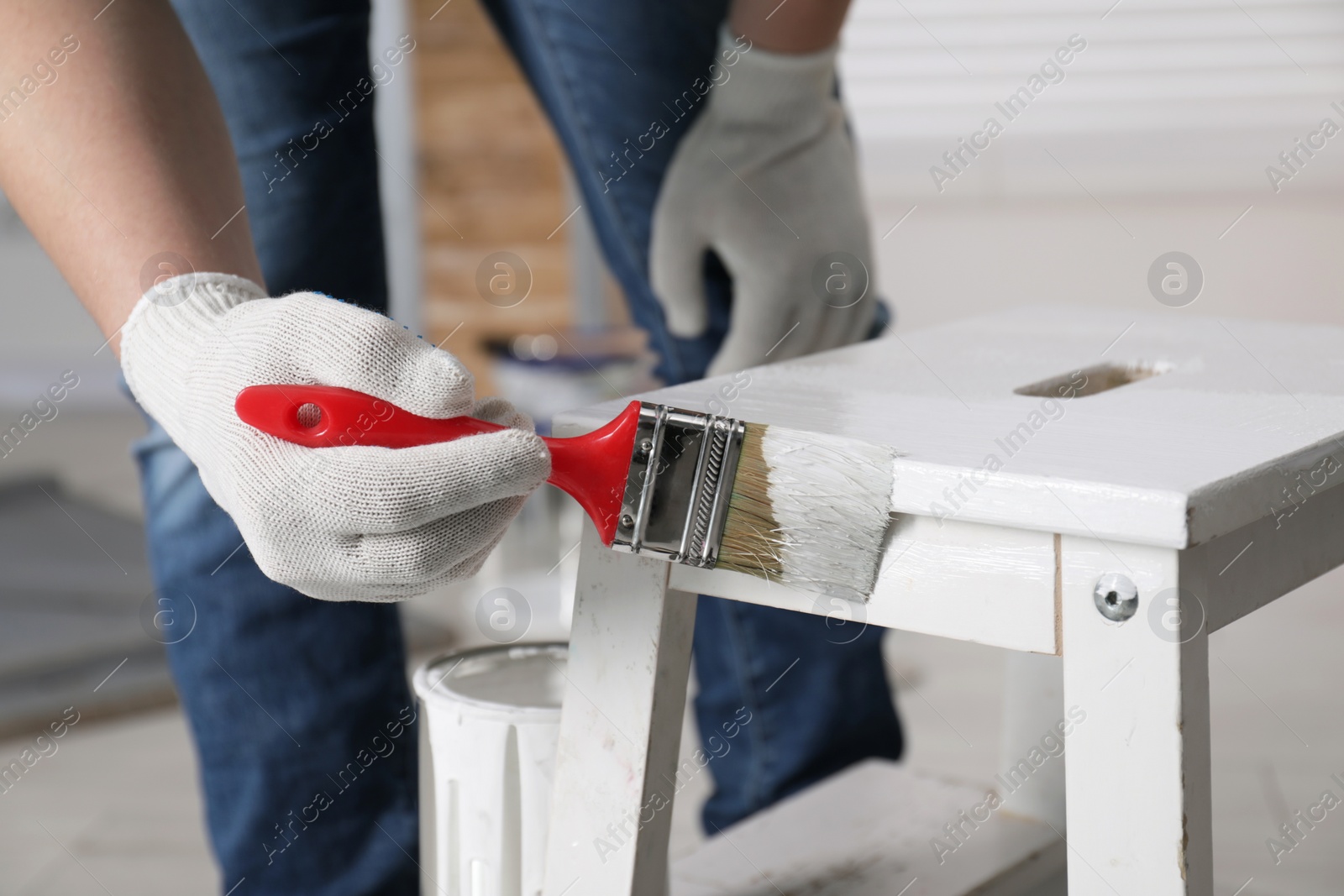 Photo of Man using brush to paint bekvam with white dye indoors, closeup