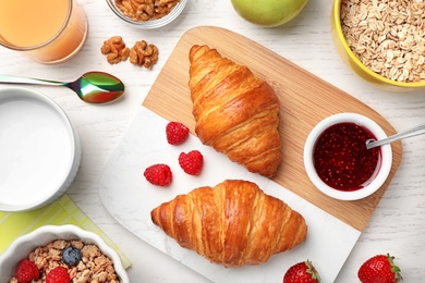 Tasty breakfast with croissants served on white wooden table, flat lay