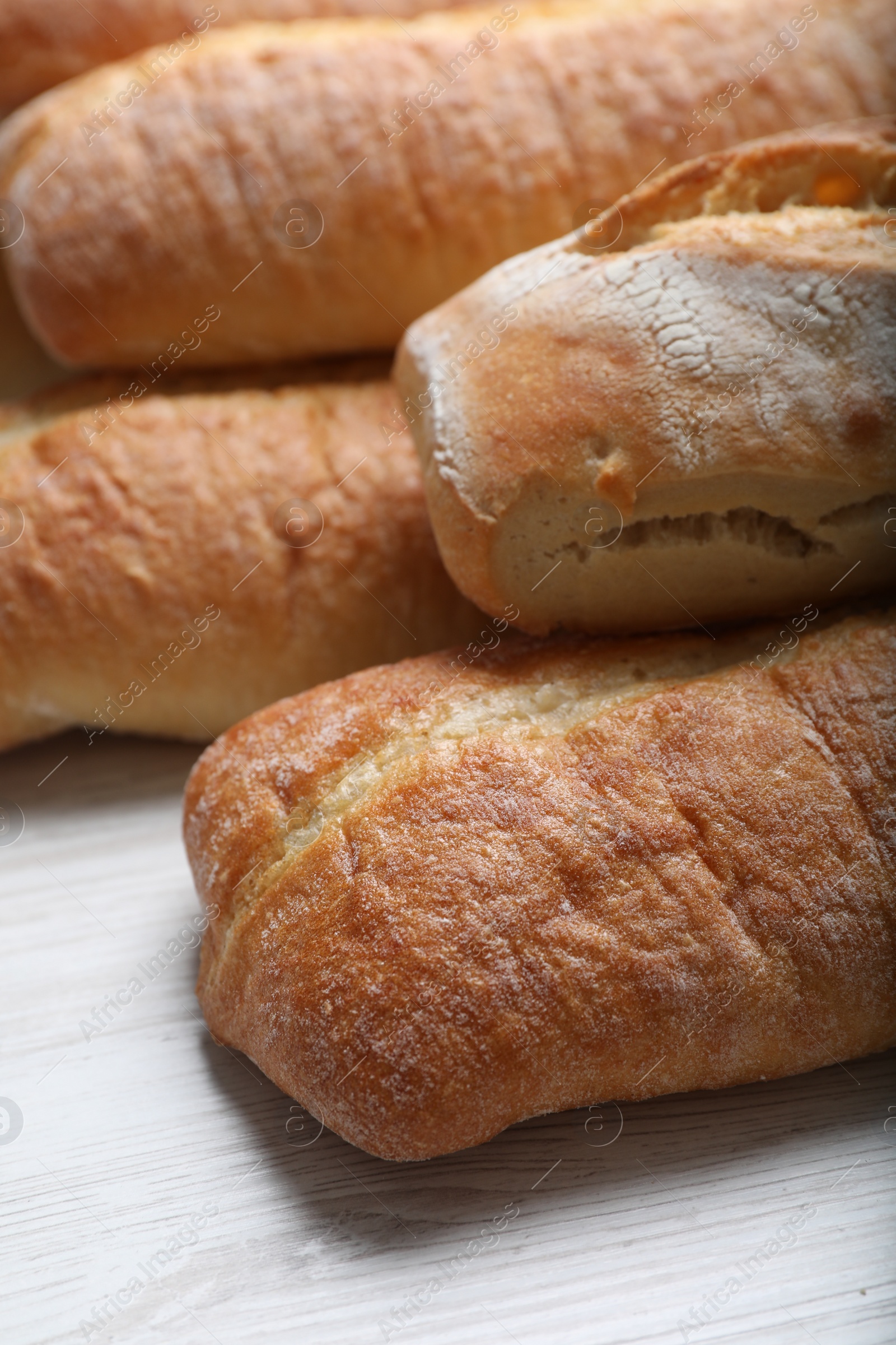 Photo of Tasty baguettes on white wooden table, closeup