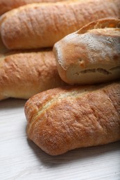 Photo of Tasty baguettes on white wooden table, closeup