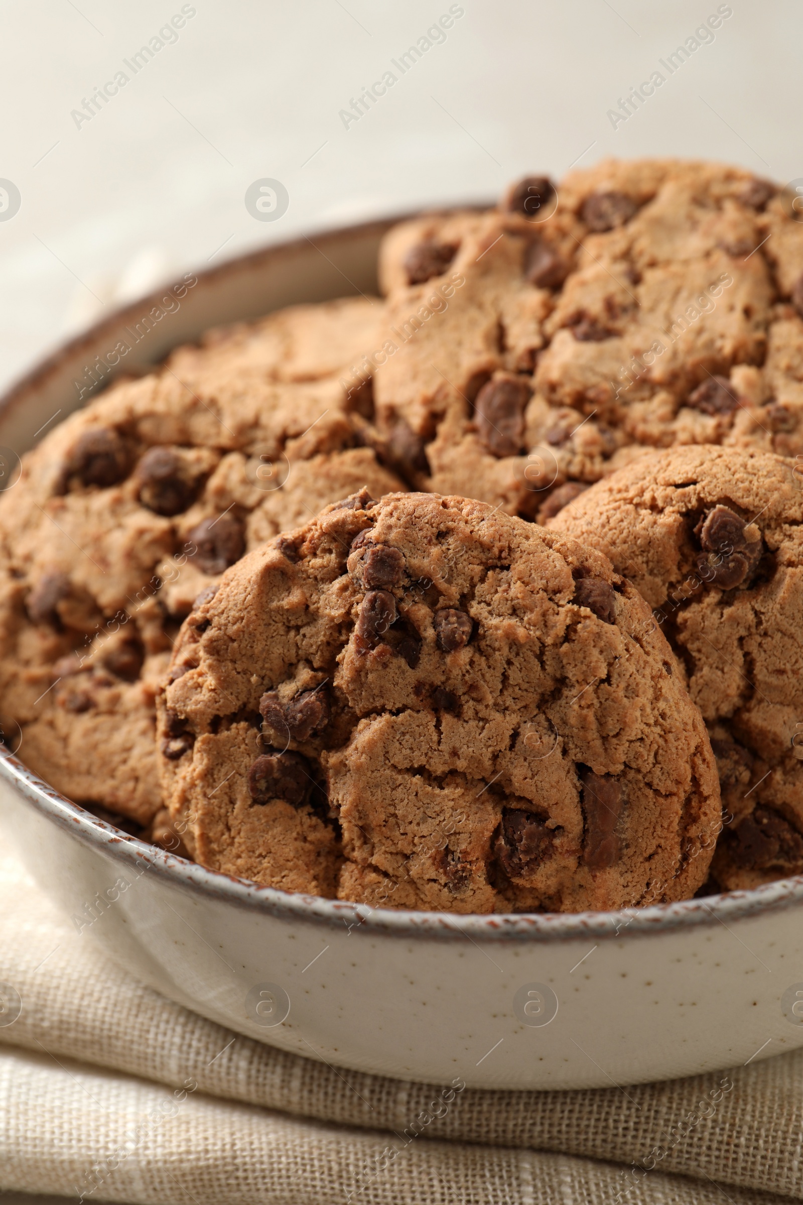 Photo of Delicious chocolate chip cookies in bowl on table, closeup