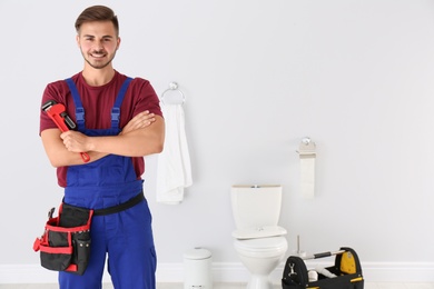 Photo of Young man with plumber wrench and toilet bowl on background