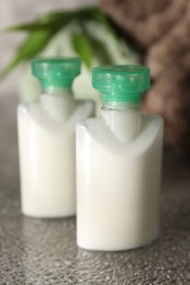 Mini bottles of cosmetic products on grey textured table