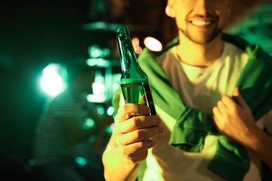 Photo of Man with beer celebrating St Patrick's day in pub, focus on hand
