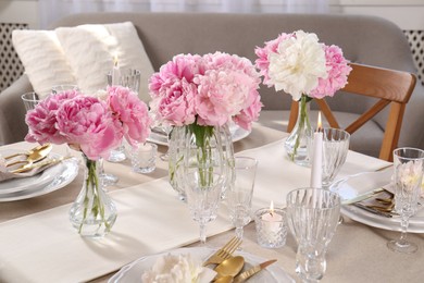 Photo of Stylish table setting with beautiful peonies and burning candle indoors