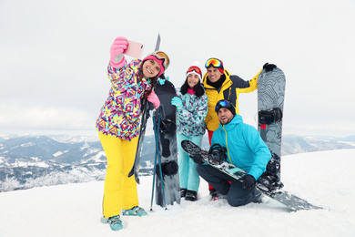 Photo of Group of friends taking selfie in snowy mountains. Winter vacation