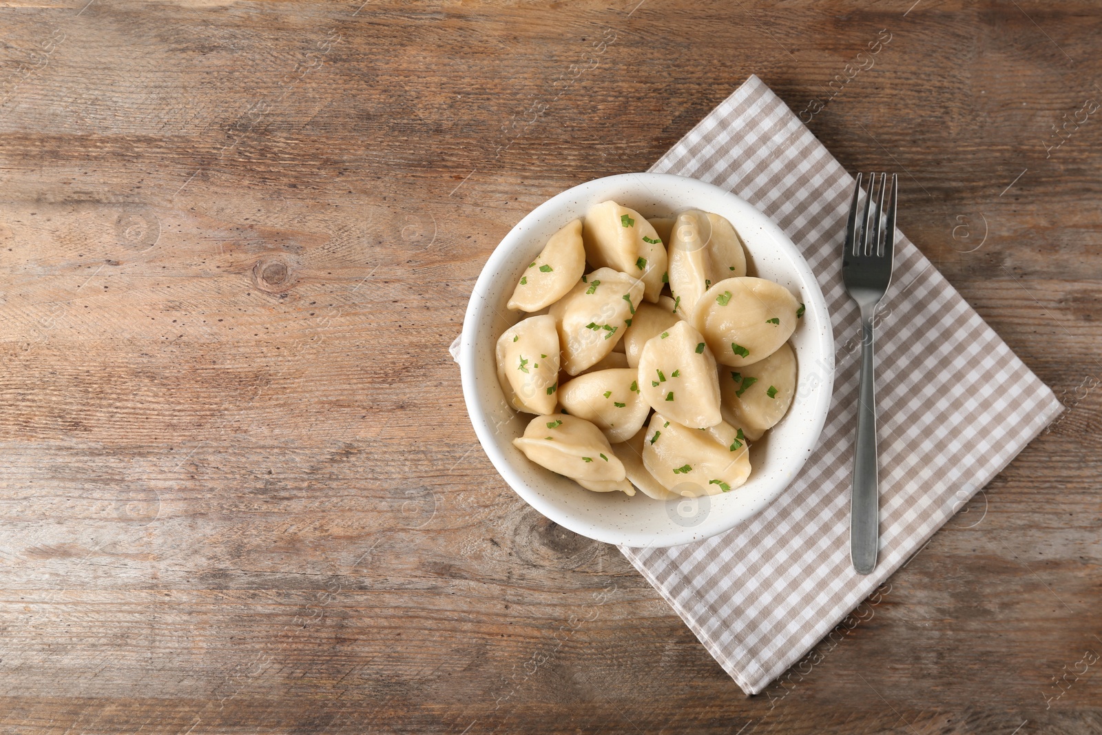 Photo of Delicious cooked dumplings served on wooden table, flat lay. Space for text