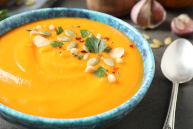 Photo of Delicious pumpkin soup in bowl on table, closeup