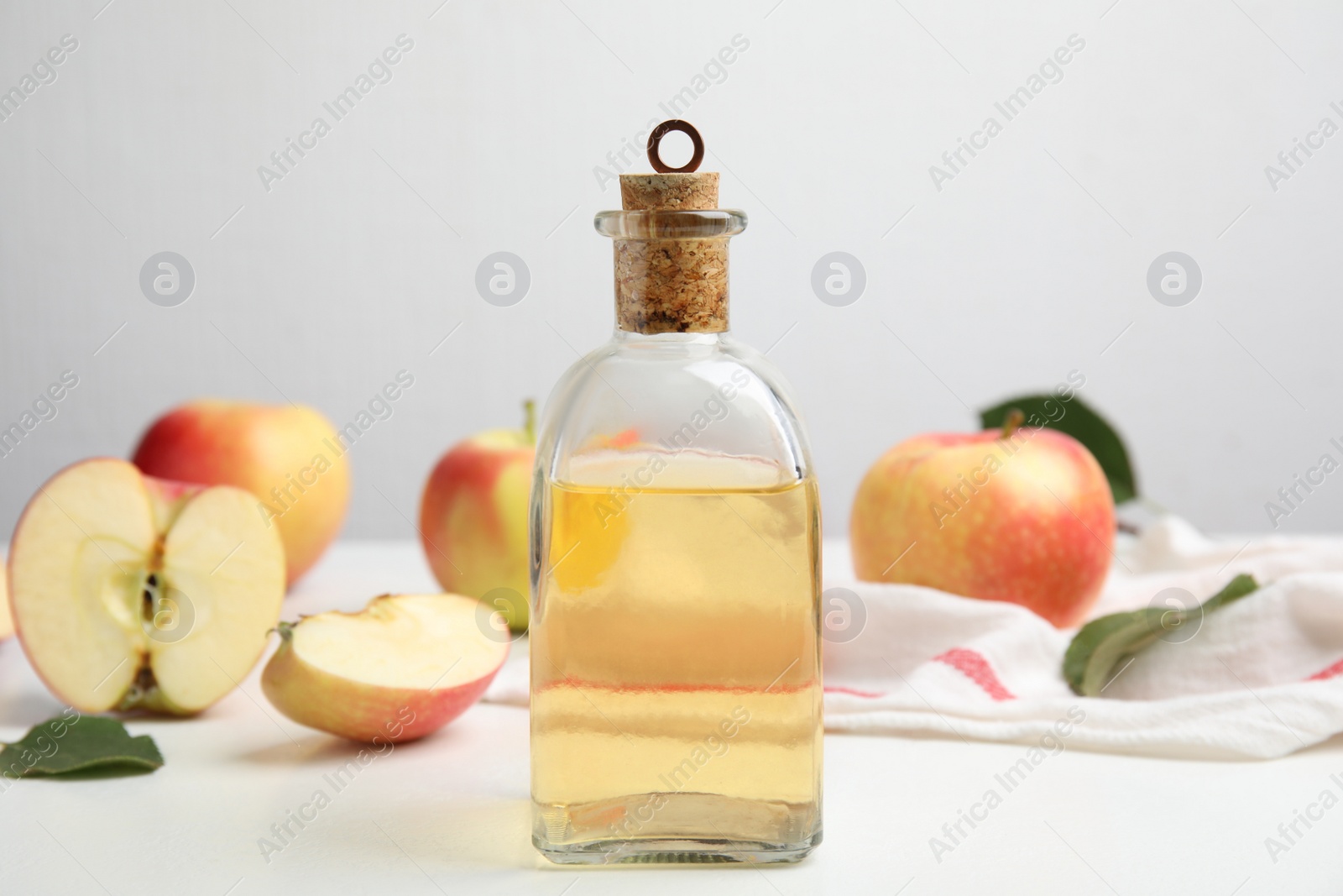 Photo of Natural apple vinegar and fresh fruits on white table