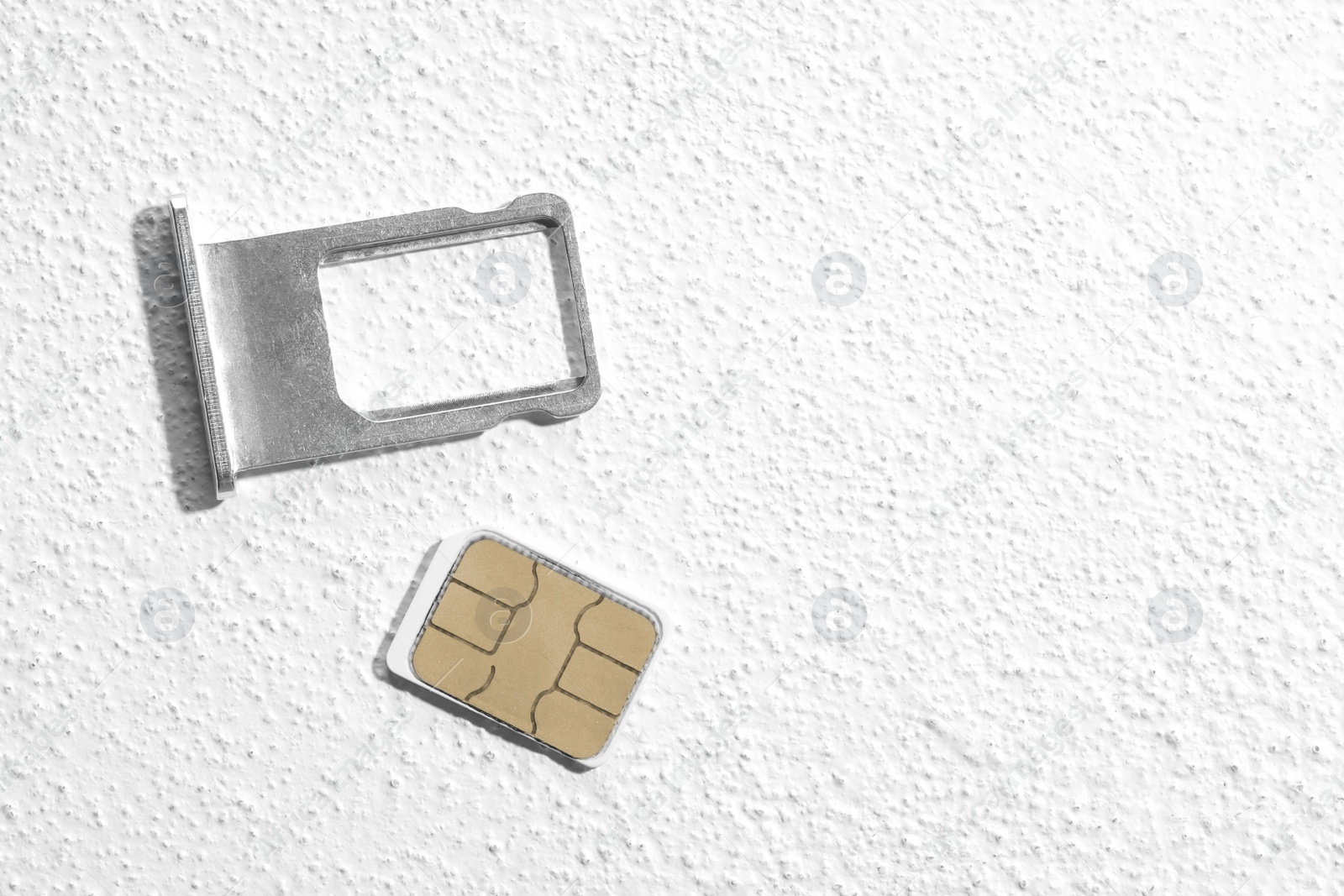Photo of SIM card and tray on white stone background, flat lay. Space for text