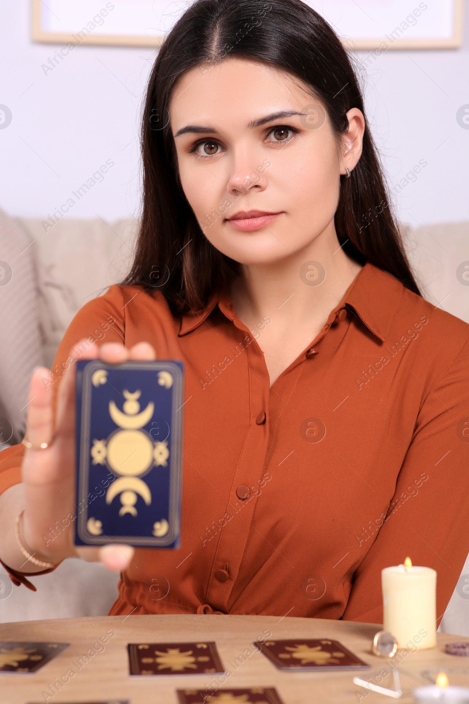 Photo of Soothsayer showing tarot cards at table indoors. Fortune telling