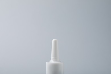 Photo of Bottle of nasal spray on grey background, closeup. Space for text