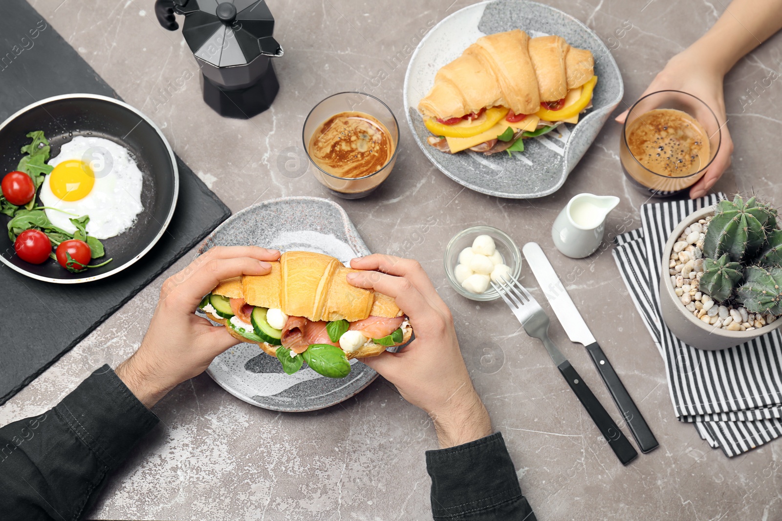 Photo of People eating tasty croissant sandwiches at table