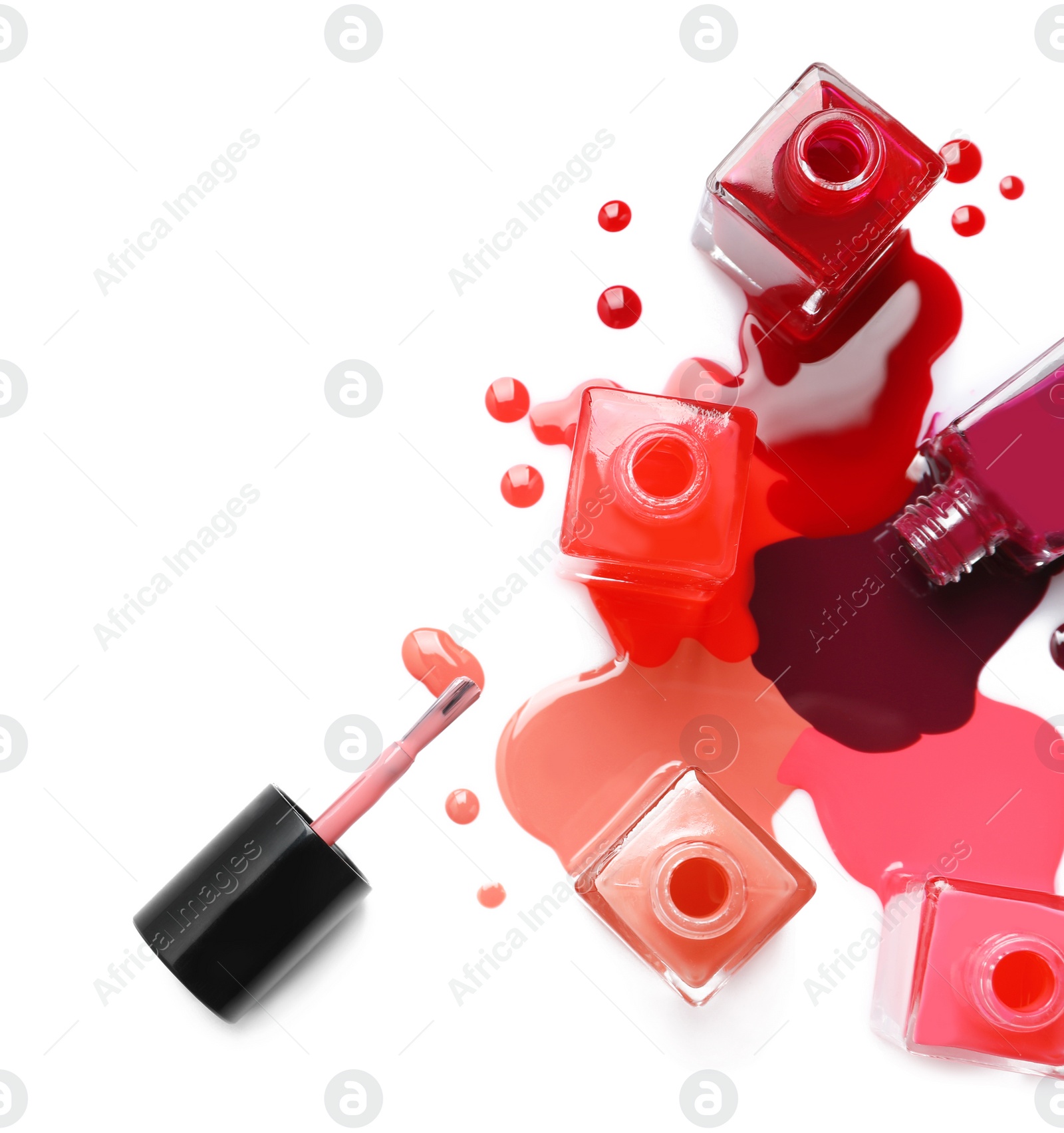 Photo of Spilled different nail polishes with bottles on white background, top view