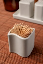 Photo of Holder with many toothpicks on bamboo mat, closeup