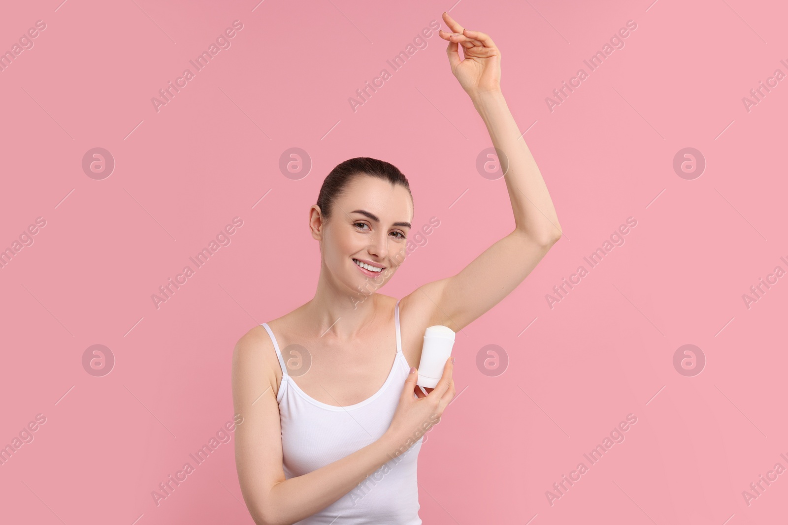 Photo of Beautiful woman applying deodorant on pink background