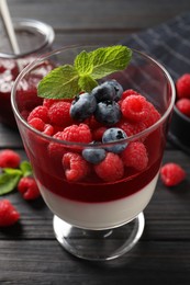 Photo of Delicious panna cotta with berries on black wooden table, closeup