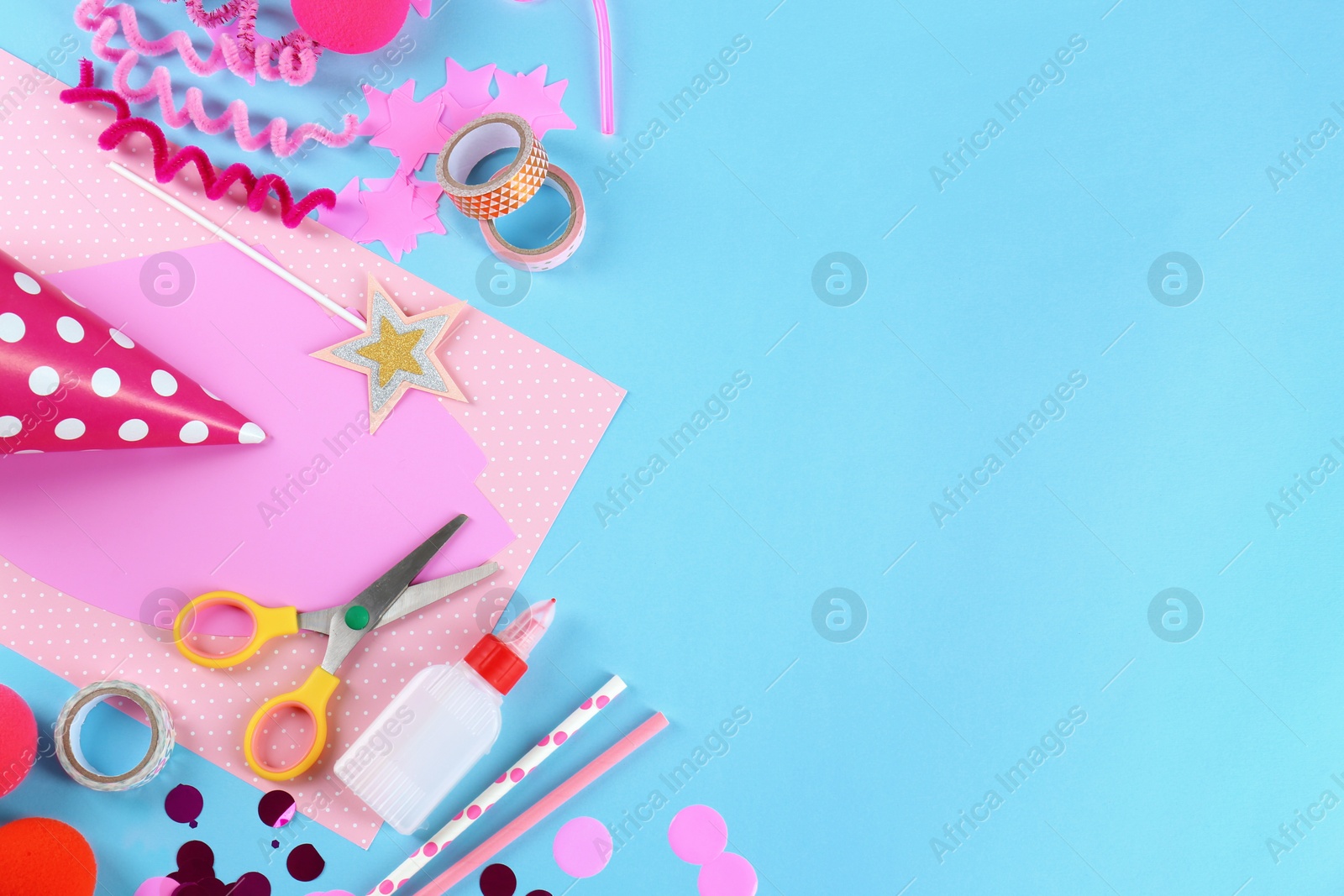 Photo of Flat lay composition with different materials to create party hats on light blue background, space for text. Handmade decoration