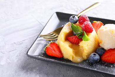 Photo of Tasty vanilla fondant with white chocolate, berries and ice cream on light grey textured table, closeup