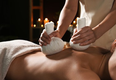 Photo of Young woman receiving herbal bag massage in spa salon, closeup