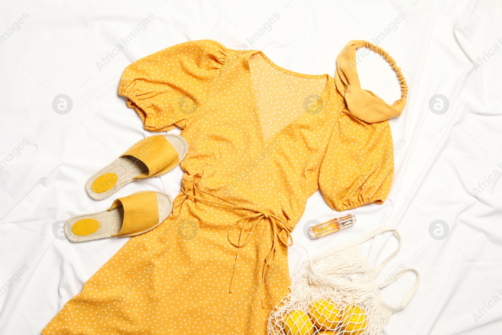 Photo of Flat lay composition with stylish yellow dress on white fabric