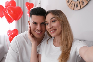 Photo of Lovely couple taking selfie at home. Valentine's day celebration