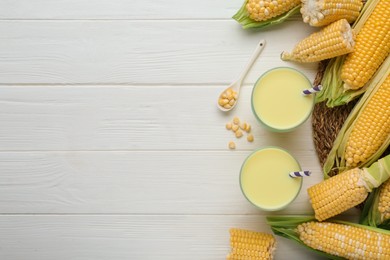 Photo of Corn juice and cobs on white wooden table, flat lay. Space for text