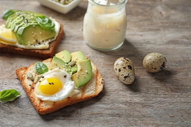 Toast bread with fried egg and avocado slices on wooden table