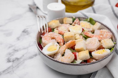 Photo of Delicious Caesar salad with shrimps served on white marble table, closeup