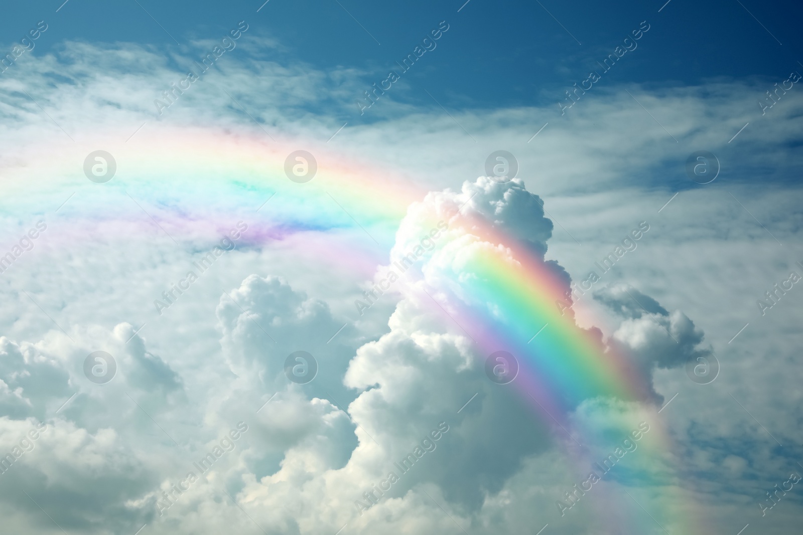 Image of Beautiful view of bright rainbow in blue sky on sunny day