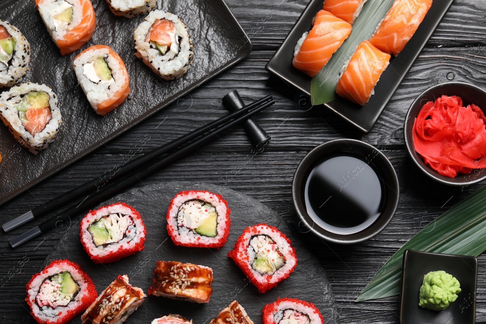 Photo of Flat lay composition with different sushi rolls on black wooden table