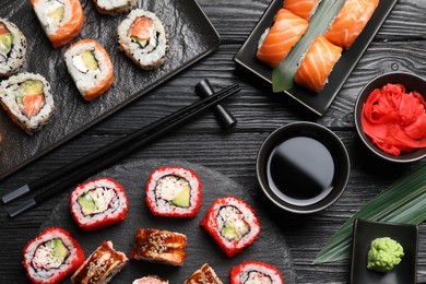 Flat lay composition with different sushi rolls on black wooden table