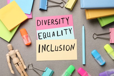 Photo of Words Diversity Equality Inclusion and stationery on grey background, flat lay